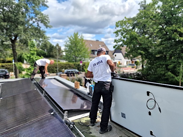 Montage von Solarmodulen auf einer flachen Dachfläche an einem Wohngebäude
